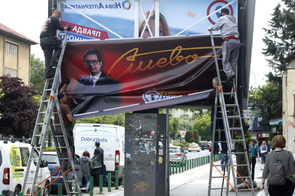 Рабочие снимают агитационный баннер, где изображен теперь уже бывший президент Северной Македонии Стево Пендаровски