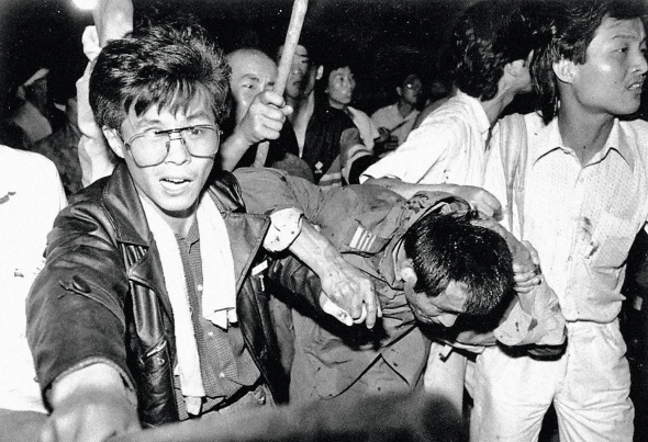 Побитого військовослужбовця виводять із натовпу протестувальників на площі Тяньаньмень у Пекіні в ніч на 4 червня 1989-го. Протягом квітня-травня у столиці Китаю студенти проводили протести із закликами до лібералізації життя. Влада жорстоко розігнала їх, застосувала танки і бронетехніку. Цивільним вдалося спалити більш як 10 танків. У сутичках загинуло понад 300 осіб. Після того в Китаї провели арешти, посилили цензуру та контроль за громадянами