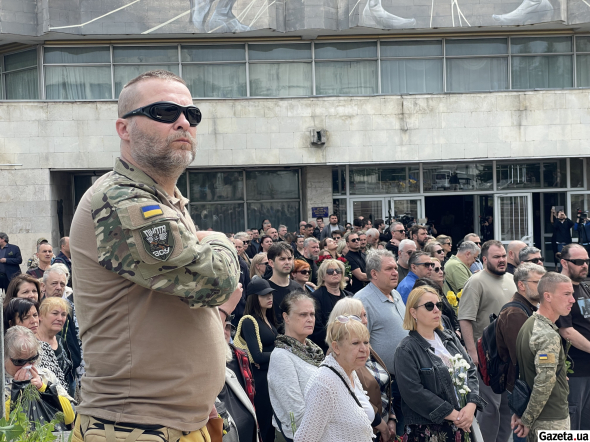 Присутні стають на коліно, коли труну проносять повз
