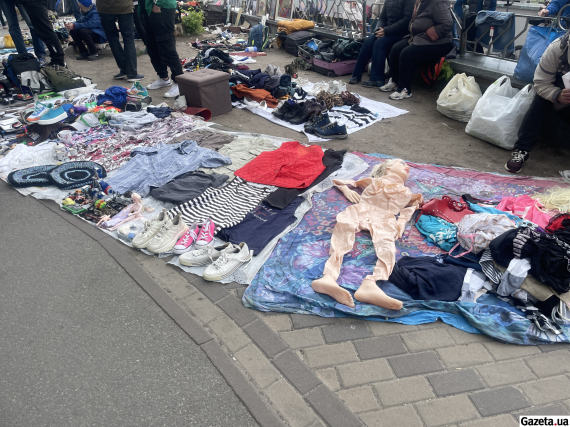 За павільйонами - люди торгують просто неба, розклавши товари на ковдрах