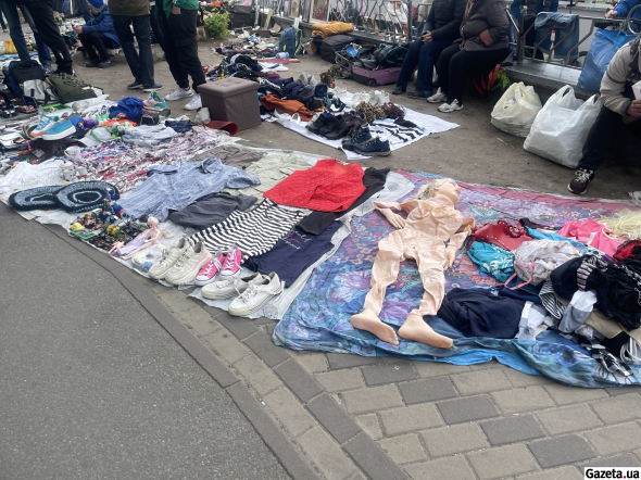 За павильонами - люди торгуют под открытым небом, разложив товары на одеялах