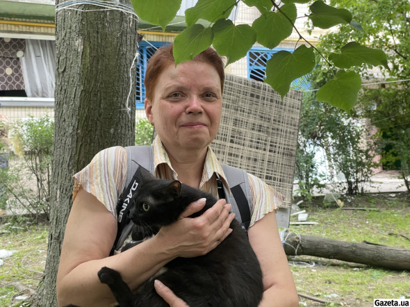 57-річна Оксана Загородня тримає на руках врятовану кішку Азу, яку знайшли рятувальники після того, як жінка двічі поверталася до квартири під час обстрілу