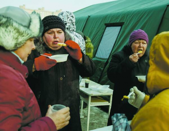 Жителі Авдіївки їдять у мобільному пункті обігріву після обстрілу міських будівель 3 лютого. Порція містить кашу, суп і чай