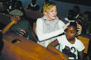 ­Мадонна в школі в ­Малаві сидить поруч із при­йомними сином Девідом та донькою Мерсі. Має шестеро дітей. Двоє старших — її біологічні