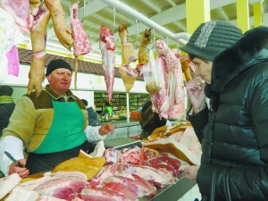 Продавець Валерій Ящук дає скуштувати сало клієнтці на ринку Урожай у Вінниці. Кілограм коштує 45–50 гривень. Свинину продає по 75 гривень, яловичину — за 108