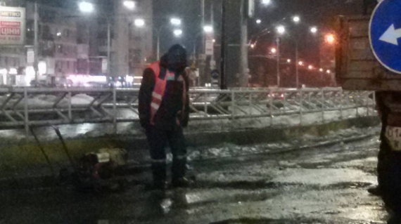 Працівник Київавтодору затоптує яму на дорозі на пл. Севастопольській / 24 лютого 2017 року