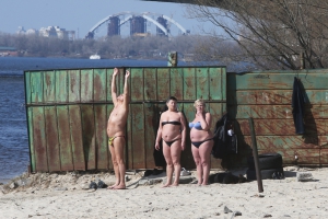 Чоловік і дві жінки засмагають на пляжі у столичному Гідропарку 22 березня