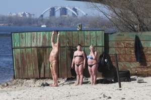 Чоловік і дві жінки засмагають на пляжі у столичному Гідропарку 22 березня