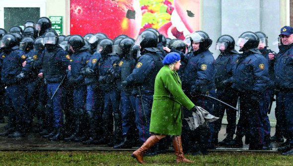 Жінка йде повз спецпризначенців на початку протестів 25 березня в Мінську. Люди вийшли на вулиці з нагоди Дня волі та проти запровадження податку на дармоїдство