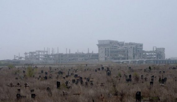 За разбомленным кладбищем видны остатки Донецкого аэропорта