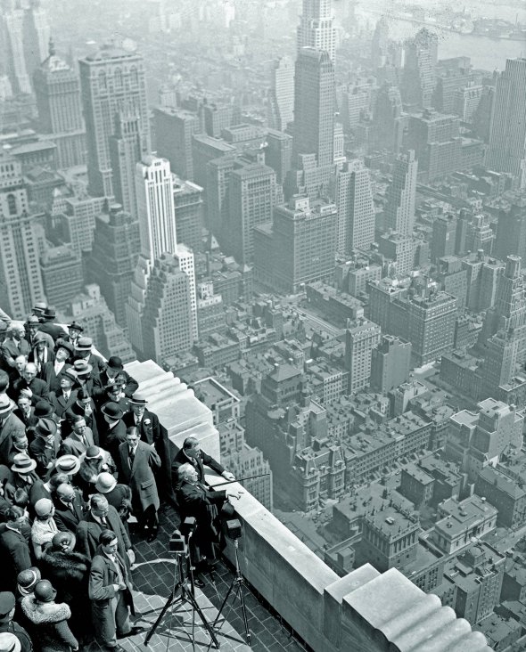 1 травня 1931 року колишній губернатор Нью-Йорка Альфред Сміт і чинний губернатор Франклін Рузвельт оглядають місто з даху хмарочоса Empire State Building – ”Будинок імперського штату” (на фото праворуч). Майданчик розташований на висоті 373 метри. Того дня відкрили 103-поверхову офісну будівлю. До 1970-го вона була найвищою у світі – 443 метри разом зі шпилем. Споруджували її менше року. В середньому за тиждень зводили чотири з половиною поверхи. На майданчику працювали понад три тисячі осіб. Шість чоловік загинули. У США була економічна криза, тому більшість офісів тривалий час залишалися порожні. Будівля почала приносити прибуток через 20 років