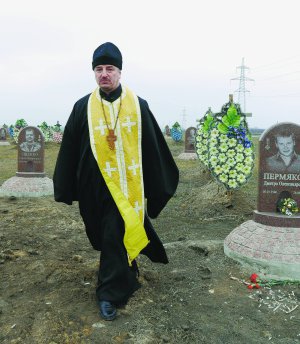 Отець Дмитро Поворотній іде Краснопільським кладовищем у Дніпрі. Тут ховають загиблих у зоні АТО українських бійців