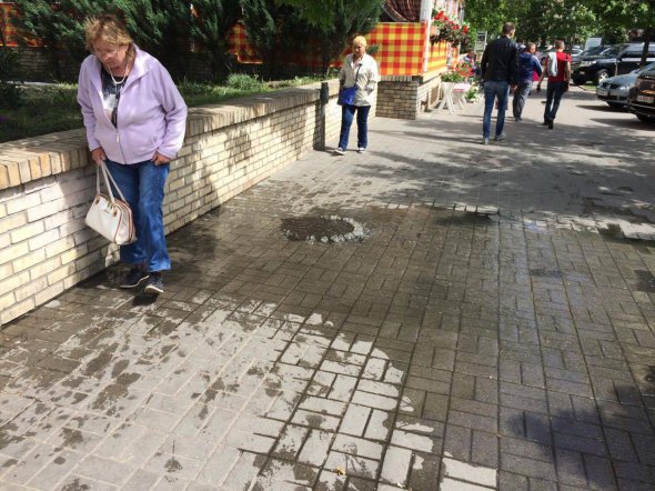 Пішоходи минають калюжу, утворену від пориву каналізації біля метро Арсенальна