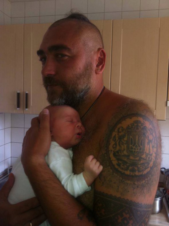Український "Санта" Володимир Регеша тримає на руках немовля. На плечі Великий герб України