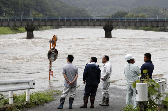 Эксперты осматривают затопленную дорогу в Миоши, префектура Хиросима