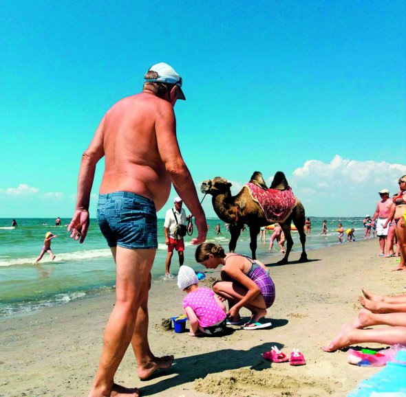 Люди відпочивають на пляжі в Коблевому на Одещині 10 липня. Температура морської води цього дня в регіоні становила  20 градусів тепла, повітря прогрілося до плюс 28. За катання на верблюді правлять 50 гривень