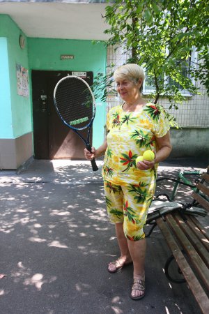 Галина Горяна стоїть у тенісному костюмі біля власного будинку в столиці. На змагання з тенісу їздить за кордон. У своїй віковій категорії здобуває перемоги