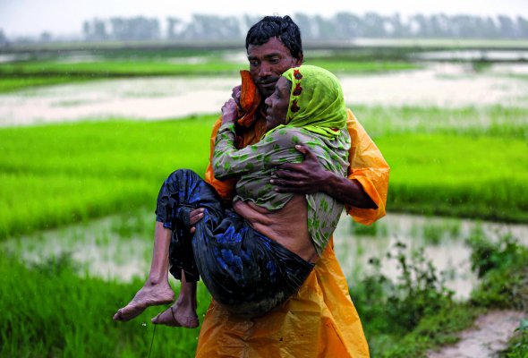 Чоловік національності рохінджа переносить жінку через річку на кордоні М’янми і Бангладеш. До організованих пунктів пропуску стоять довжелезні черги біженців