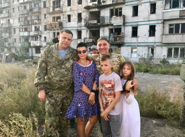 Глава ДНР Александр Захарченко и пропагандист Захар Прилепин фотографируются с женщиной и детьми на фоне разрушенной многоэтажки