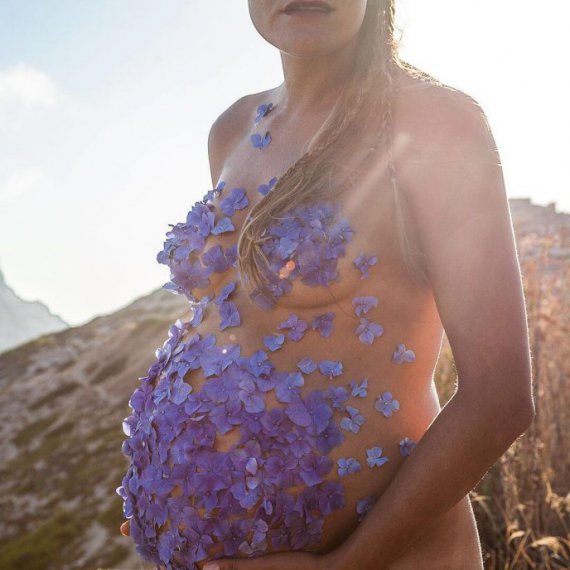 Фотосесія вагітної із пелюстками на грудях і животі