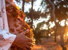 Фотосесія вагітної із пелюстками на грудях і животі