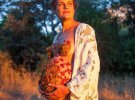 Фотосесія вагітної із пелюстками на грудях і животі