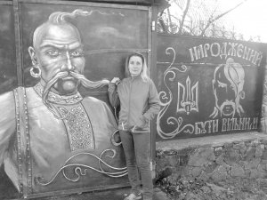 Олена Єпіфанова стоїть біля своїх воріт у Смілі на Черкащині. Її подвір’я розмалював козаками 35-річний Сергій. Малювати навчився у в’язниці