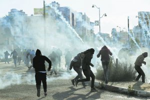 Демонстранти біжать від сльозогінного газу, застосованого ізраїльськими військами під час зіткнень поблизу єврейського поселення Бейт-Ель, 7 грудня 2017 року. Палестинці протестують проти визнання Сполученими Штатами Америки Єрусалима столицею Ізраїлю