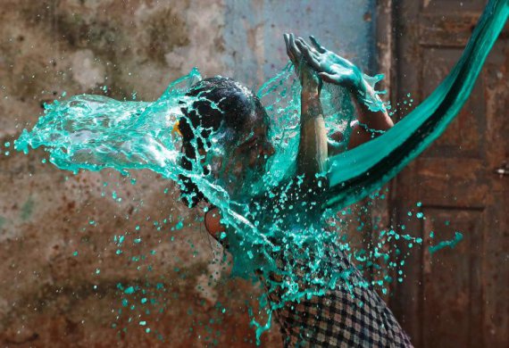 Девушка реагирует на цветную воду, которую вылили на ее лицо во время фестиваля Холи. Мумбаи. Индия