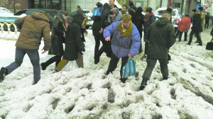 Люди намагаються перейти вулицю в центрі міста 19 грудня. На пішохідних переходах утворилася глибока ”каша”, бо сніг із доріг розсунули до тротуарів