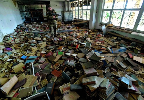 Український військовослужбовець  оглядає 3 вересня 2017 року  занедбану бібліотеку  в прифронтовому місті Мар’їнка