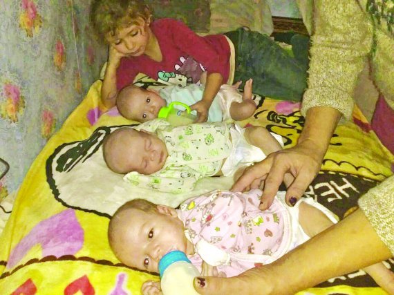 Наталія Самаріна із дочкою 5-річною Аліною годує трійнят у себе вдома через місяць після народження