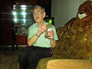 Олесь Гопанчук показує пляшку власного вина у себе в квартирі. Напоєм лікує хвороби