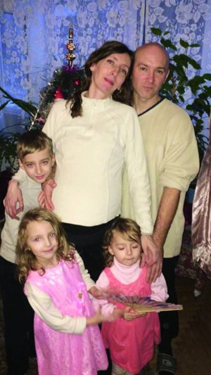Тетяна Медун стоїть удома із чоловіком Сергієм і дітьми — 9-річним Олександром, Ксенією, 7 років, та 4-річною Марією