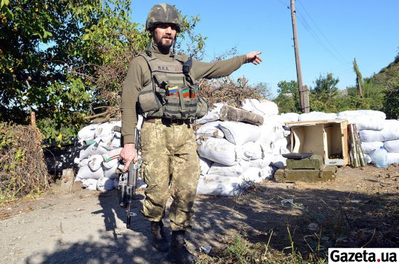 Украинский боец на одном из передовых постов в Марьинке показывает на позиции сепаратистов, в которых не более 200 метров. Сентябрь 2015