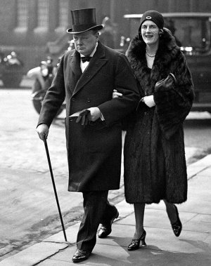 Уинстон Черчилль в цилиндре, длинном пальто и  тростью, идет в Вестминстерское аббатство с женой Клементиной в 1930 году