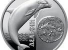 На реверсе монеты слева на зеркальном фоне изображен дельфин, стилизованные волны, справа от которых - вертикальная надпись Дельфин.