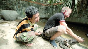 Андрій Зрожевський чистить зуби крокодилові на фермі в Камбоджі