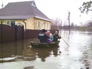 Поліцейські евакуюють жінку з дитиною із затопленого дому в райцентрі Охтирка на Сумщині. Там вийшла з берегів однойменна річка. Залила 25 будинків