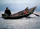 Рыбак Вячеслав Басов ставит сети, а его сын 10-летний Толя управляет лодкой при помощи самодельных весел.
