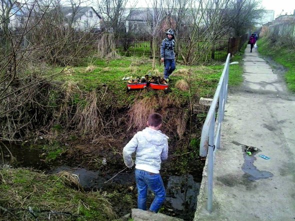 13-річний Максим Панасюк із товаришем прибирають навколо пішохідного містка поблизу старої панчішної фабрики на околиці Сокаля Львівської області