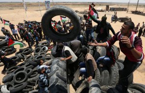 Палестинці збирають шини, щоб підпалити під час протестів на кордоні між Ізраїлем та Сектором Газа 15 травня 2018 року. За день до того Сполучені Штати перенесли своє посольство з Тель-­Авіва до Єрусалима. Палестинці вважають місто своєю столицею