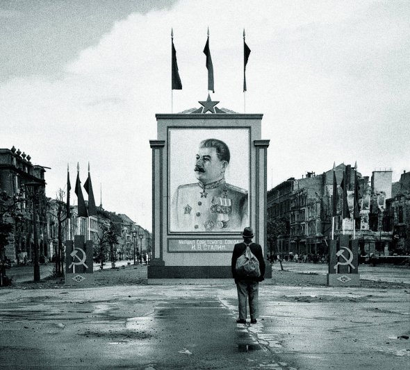 3 червня 1945 року чоловік розглядає плакат із зображенням глави уряду СРСР Йосипа Сталіна на бульварі Унтер-ден-Лінден у Берліні. Після капітуляції Німеччини ця частина міста відійшла до радянської зони окупації. На цьому бульварі відкрили посольство СРСР