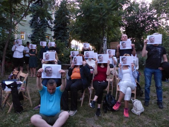 Все присутствующие прикрыли свои лица фотографиями Сенцова