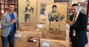 Віталій (праворуч) та Володимир Клички позують біля стенду із зображенням чемпіонів світу з боксу Мухаммеда Алі та Джо Фрезера у Канастоті, США