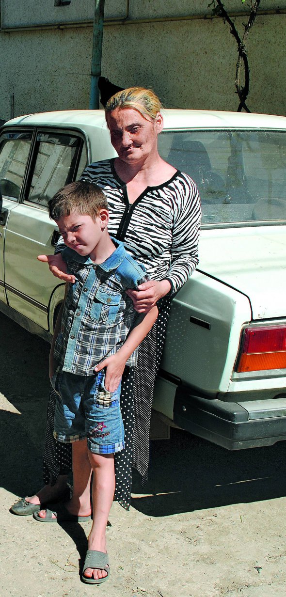 Мати Миколи Бурмека-Дюрі Людмила стоїть на подвір’ї свого будинку з онуком Русланом. Закінчила шість класів школи. Їздить на заробітки до Києва – продає на вулиці квіти