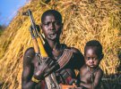 Женщина мурси с ребенком на руках и АК-47
