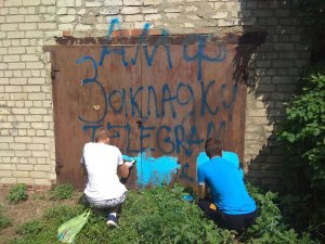 Двоє школярів зафарбовують рекламний напис інтернет-магазину наркотиків на гаражі в околиці Бахмута