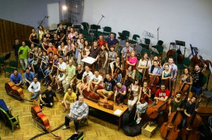 Український фестивальний оркестр фотографується з британським продюсером Мартіном Андерсоном (сидить на стільці попереду) у львівському Палаці мистецтв