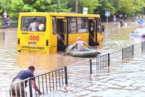 Чоловік на надувному човні підпливає до автобуса, який застряв у воді на вулиці Сахарова у Франківському районі Львова. Брав на човен по дві людини та перевозив на другий бік вулиці. Злива, що затопила центр міста, пройшла 17 серпня. Тривала 45 хвилин